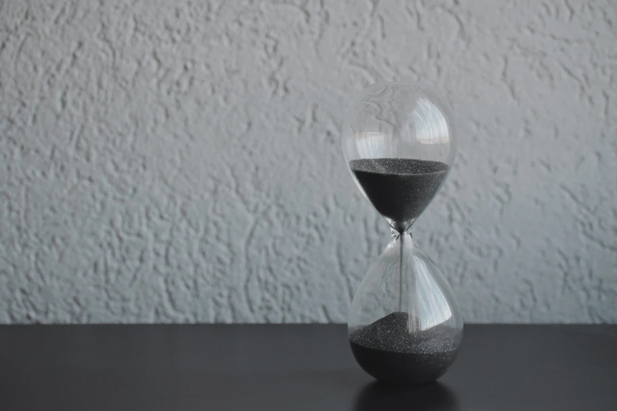 Image of an hourglass on a table representing the concept of time availability when considering a project manager